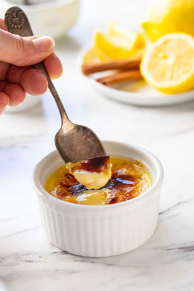 A ramekin of Crema Catalan or Spanish custard with a spoon of custard and caramelized sugar
