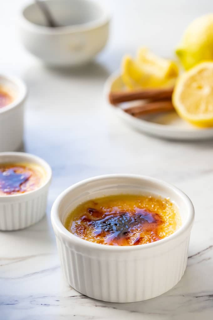 Close up of this Crema Catalana dessert recipe with lemons and cinnamon in the background.