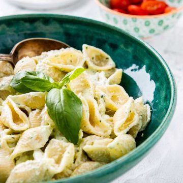 Close up shot of the pasta with yogurt sauce garnished with a sprig of basil.