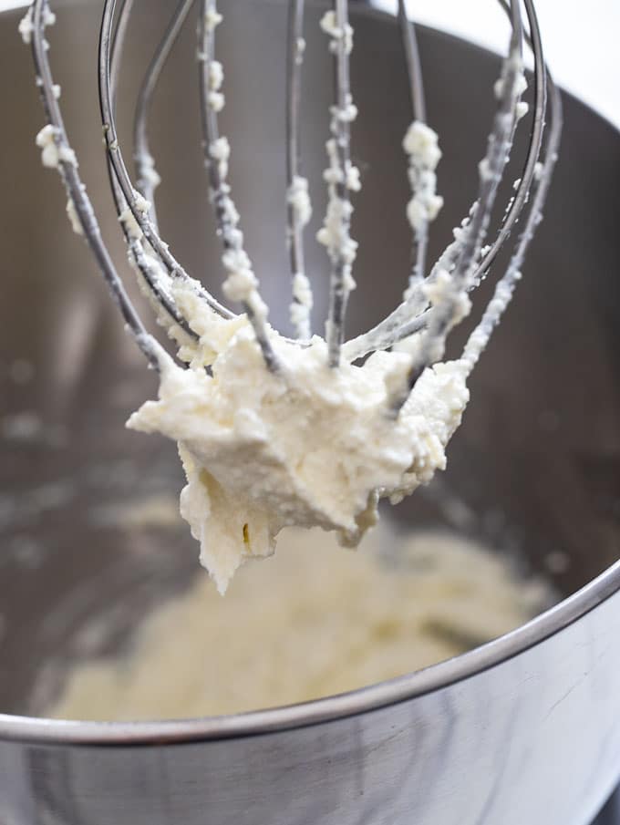 Close up shot of a beater with the whipped ricotta clinging to it.