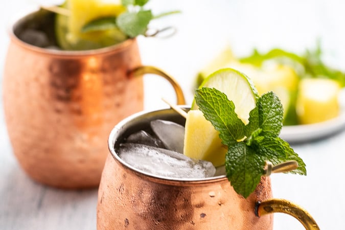 Close up of this tequila mule - a combination of tequila and ginger beer with a lime, pineapple and mint garnish. 
