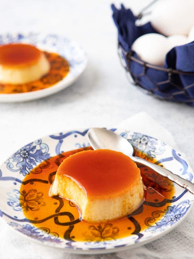 Single serving on spanish flan with caramel sauce and a spoon.