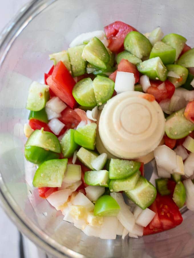 Step one of how to make gazpacho - adding the chopped vegetables to a food processor.