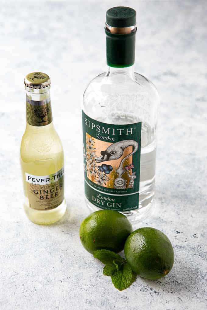 Ingredients needed for the gin mule recipe - gin, ginger beer, limes and fresh mint.