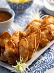 platter of crab rangoon with dipping sauce in the background.