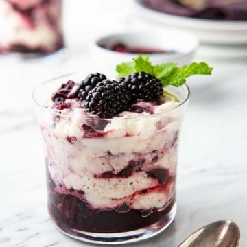 Glass of Blackberry Fool, garnished with blackberries and mint, with a spoon