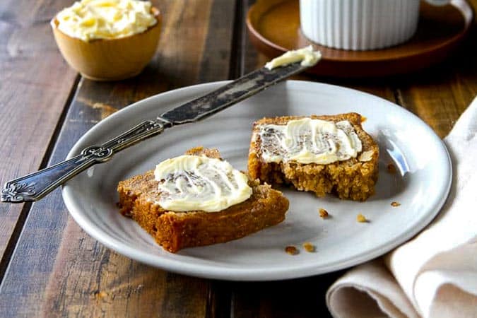 slice of date nut bread slathered with butter on a plate.