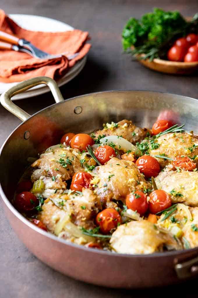 A large skillet with Chicken Contadina  with plates in the background. 
