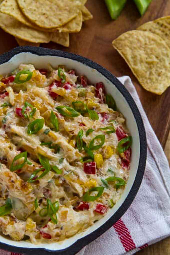 Skillet with crack corn dip with tortilla chips in the background. 