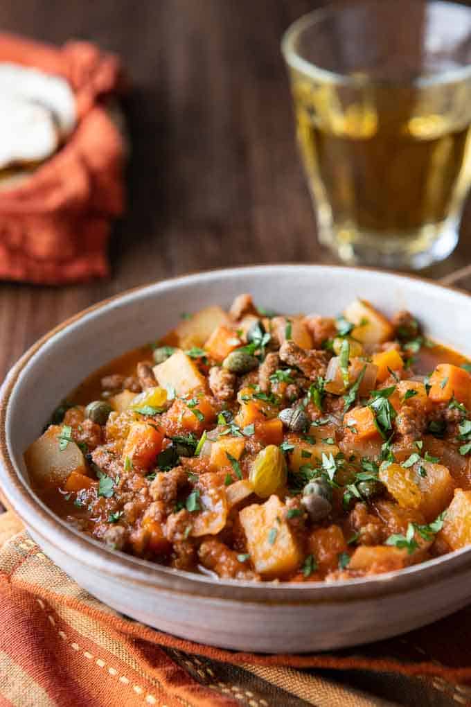 close up of a bowl with beef picadillo with tortillas in the backgrounds.