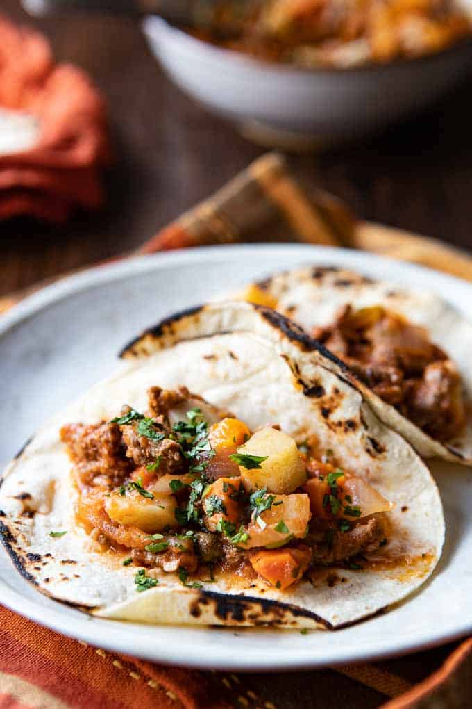 Beef Picadillo on corn tortillas on a plate.
