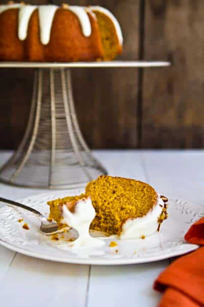 bourbon pumpkin bundt cake with bourbon cream cheese frosting on a plate with a fork.