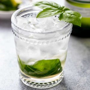 Vermouth and basil cocktail in a rocks glass with a basil leave garnish.