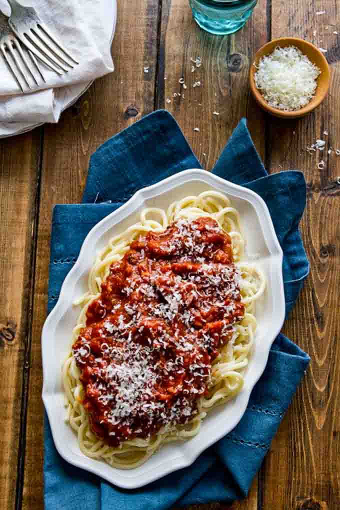 Spaghetti and meat sauce on pasta on a platter with grated parmesan