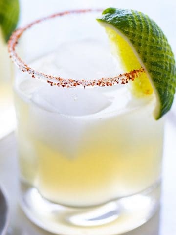 A glass of the best margarita on the rocks with a lime garnish.