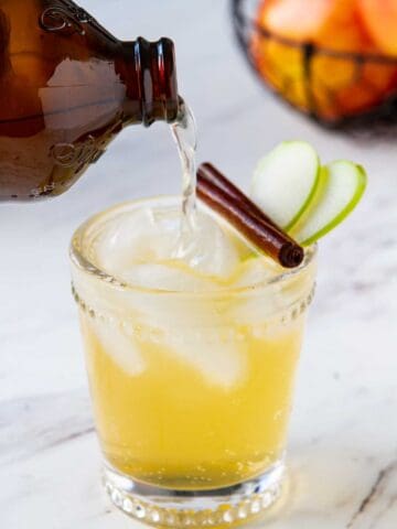 Ginger beer being poured into an apple cider cocktail.