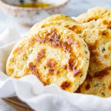 Basket with yogurt flatbreads and a bowl of olive oil in the background.