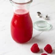 Glass jar filled with raspberry syrup.