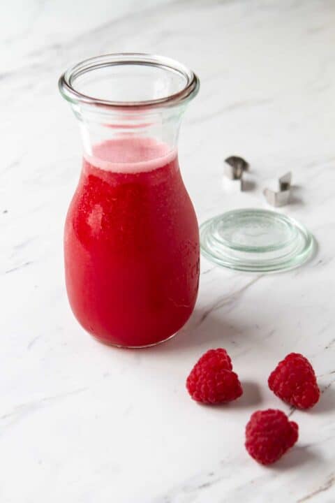 Glass jar filled with raspberry syrup.