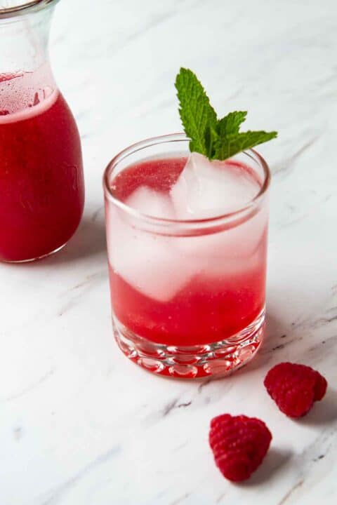 homemade raspberry syrup with sparking water in a glass. 