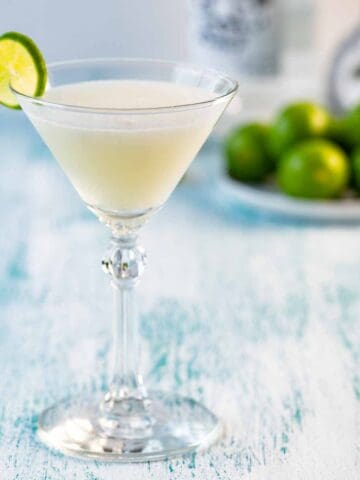 A single glass of a key lime martini with a lime wheel garnish