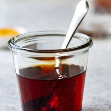 Close up of a jar with Demerara simple syrup with a spoon in it.